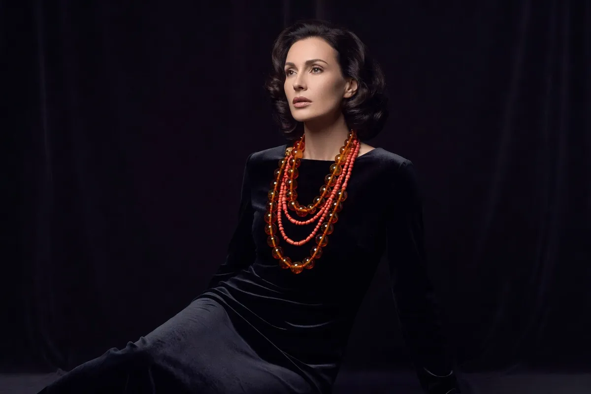 Femme portant un collier de perles d'ambre balte rondes et polies sur une robe sombre