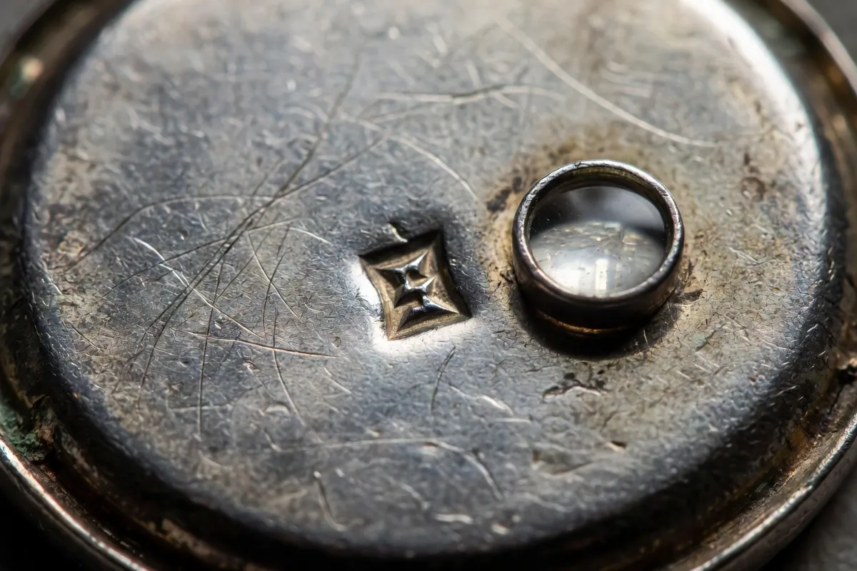 Poinçon frappé dans l'argent patiné d'un bijou ancien sous une loupe